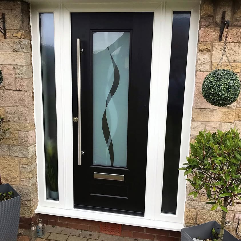 Dark front door with decorative glazing and side panels in a stone surround
